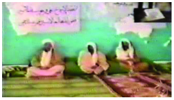 Image of Osama Bin Laden speaking on camera with 2 other men.